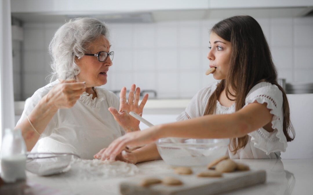 pensive grandmother with granddaughter having interesting conversation while cooking together in light modern kitchen