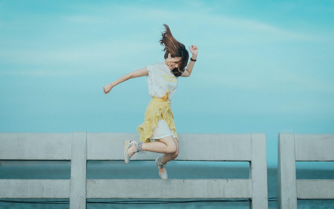 jumpshot photography of woman in white and yellow dress near body of water