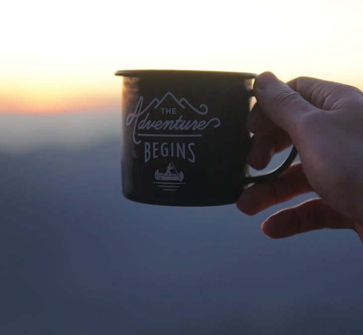 person holding black ceramic mug during sunset
